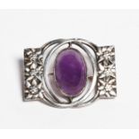 A silver and amethyst brooch, pierced and cast with foliate panels and central polished amethyst