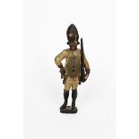 A painted wooden figural clock, modelled as a soldier holding a rifle to attention, with