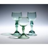 Three export green wine glasses c.1760, the cup bowls of a pale tone, raised on hollow blown stems