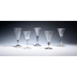Five soda wine glasses c.1750-60, four with drawn trumpet bowls over plain stems, two enclosing long
