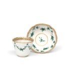 A Bristol teabowl and saucer c.1775, the generous ogee forms painted in green camaieu with flower