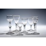 Six wine glasses c.1760-90, the bowls cut with varying designs, facets and polished ovals, raised on