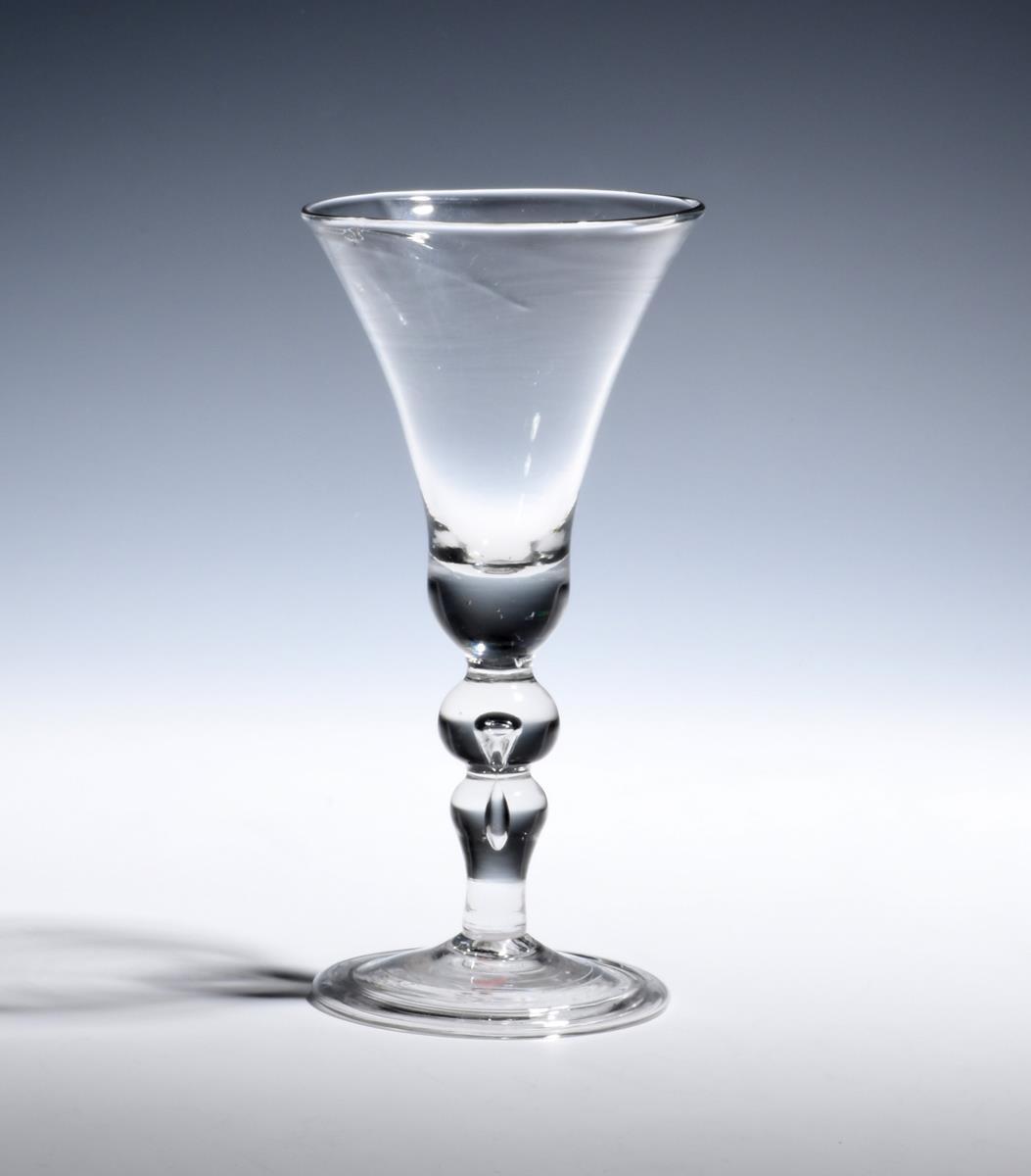 A baluster wine glass c.1725, with a generous bell bowl raised on a stem including a ball knop and