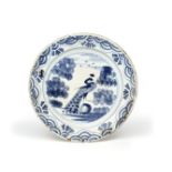 A Delft charger c.1680-90, painted in blue with a strutting peacock flanked by tall sponged trees,