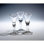 Three wine glasses c.1740-50, the bell bowls with solid bases, raised on thick plain stems, one