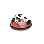 A Bilston enamel bonbonnière c.1780, modelled as a spaniel recumbent on a dark pink cushion, its