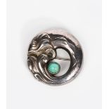 A Georg Jensen silver brooch, model no.10, circular cast with a leaping fish, set with green agate
