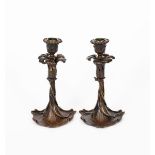 A pair of patinated bronze candlesticks possibly American, each modelled as an Art Nouveau flower