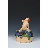 'Large Putto' M40 a large Ashtead Pottery figure, modelled seated on a bed of flowers, on