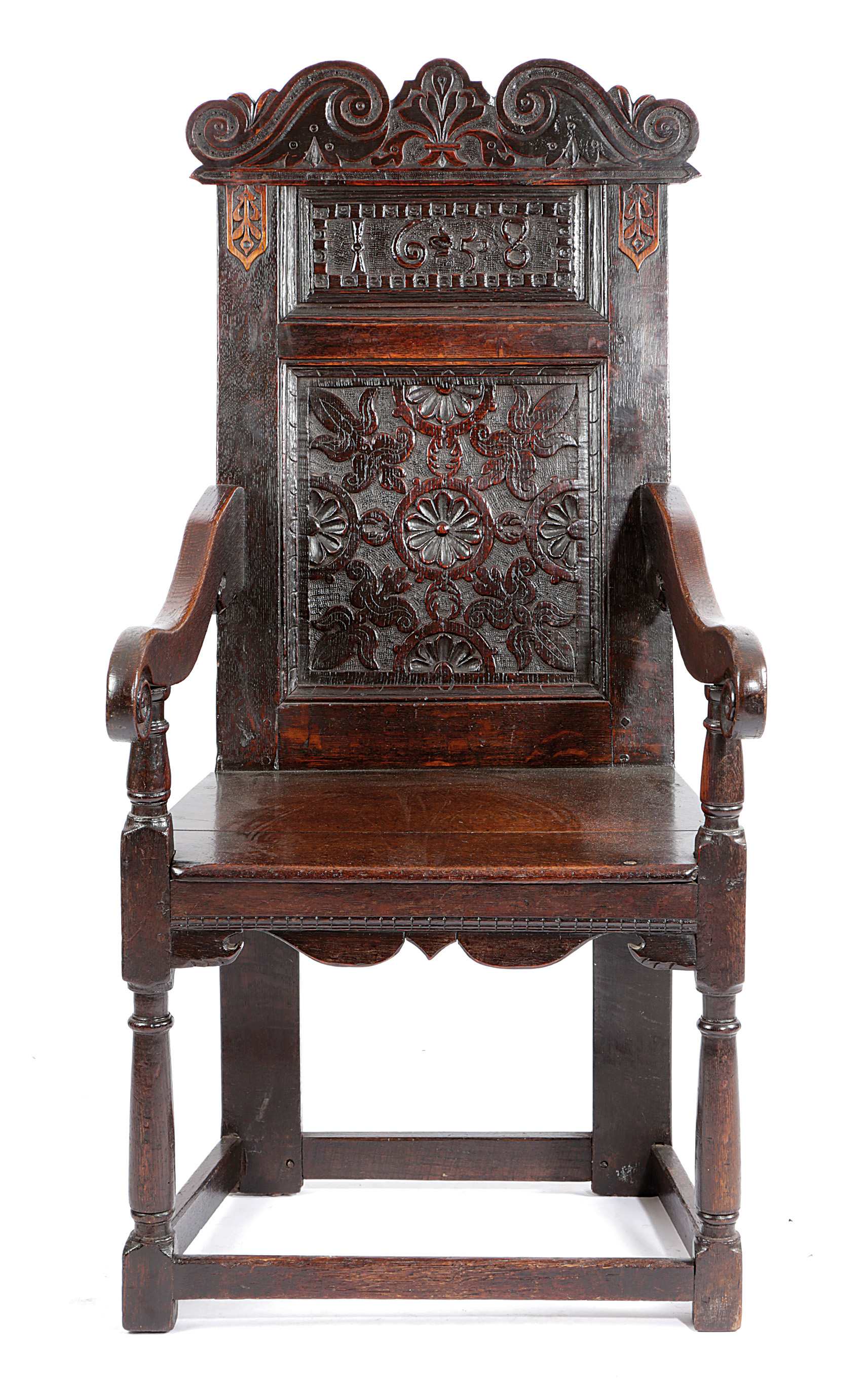 A CHARLES I OAK PANELLED BACK ARMCHAIR DATED '1638' the scroll carved crest centred with a fleur-