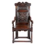 A CHARLES I OAK PANELLED BACK ARMCHAIR DATED '1638' the scroll carved crest centred with a fleur-