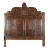 AN OAK BEDHEAD 17TH CENTURY ELEMENTS carved with scrolling leaves above a band of lunettes and