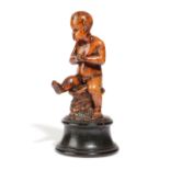 A BOXWOOD FIGURE OF A PUTTO ITALIAN OR GERMAN, LATE 17TH / EARLY 18TH CENTURY depicted seated on a a