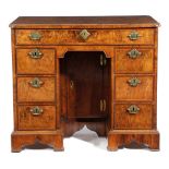 A GEORGE II WALNUT KNEEHOLE DESK C.1725 the quarter veneered top with cross and feather banding