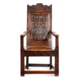 A RARE CHARLES I WALNUT PANELLED BACK ARMCHAIR DATED '1639' the undulating top rail relief carved