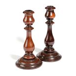 A PAIR OF EARLY VICTORIAN TREEN LIGNUM VITAE CANDLESTICKS C.1840 each with a baluster turned stem (
