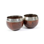 TWO TREEN SILVER MOUNTED COCONUT DIPPER CUPS C.1700 the plain rim with an engraved foliate edge,