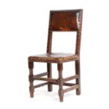 A CHARLES II OAK AND LEATHER SIDE CHAIR C.1670-80 the padded back and seat with brass studs, on