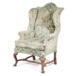 A WING ARMCHAIR IN QUEEN ANNE STYLE LATE 19TH CENTURY upholstered with fringed cut-velvet damask, on