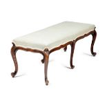 A VICTORIAN WALNUT LONG STOOL IN LOUIS XV STYLE, C.1860-70 with a needlework seat above a shaped