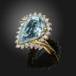 An aquamarine and diamond cluster ring, the pear-shaped aquamarine is set within a surround of round