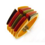 An Art Deco 'PHILADELPHIA' Bakelite bangle, the tapered bangle with vari-coloured bakelite sections,