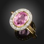 A pink tourmaline and diamond cluster ring, the oval-shaped tourmaline is set within a surround of