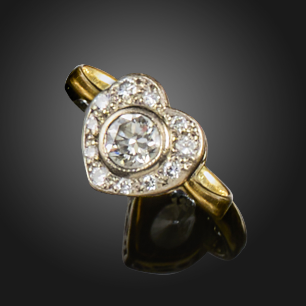 A diamond cluster ring, centred with a circular-cut diamond within a heart-shaped surround of