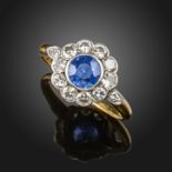 A sapphire and diamond cluster ring, the circular-cut sapphire is set within a surround of round