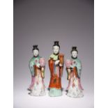 THREE CHINESE FAMILLE ROSE CANDLESTICK FIGURES OF COURT LADIES QIANLONG 1736-95 Comprising: a pair