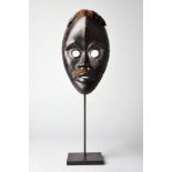 A Dan mask Ivory Coast with a vertical forehead ridge and with applied cloth and hair, 24cm high, on