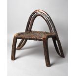 An Ethiopian chair with a one piece open channelled arched back with a woven hide seat, 57cm high.