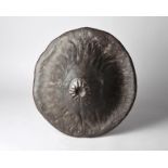 A Sidamo shield Ethiopia hide, with a central radiating motif and a leather handle, 45cm diameter.