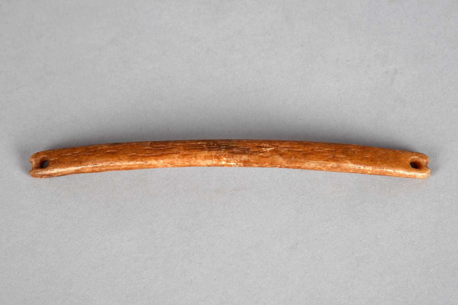An Inuit handle bag handle Arctic, 19th century bone, curved with attachment holes and grooves to
