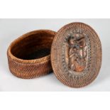 An Indonesian oblong basketry box and cover the cover inset a relief carved wood panel depicting a