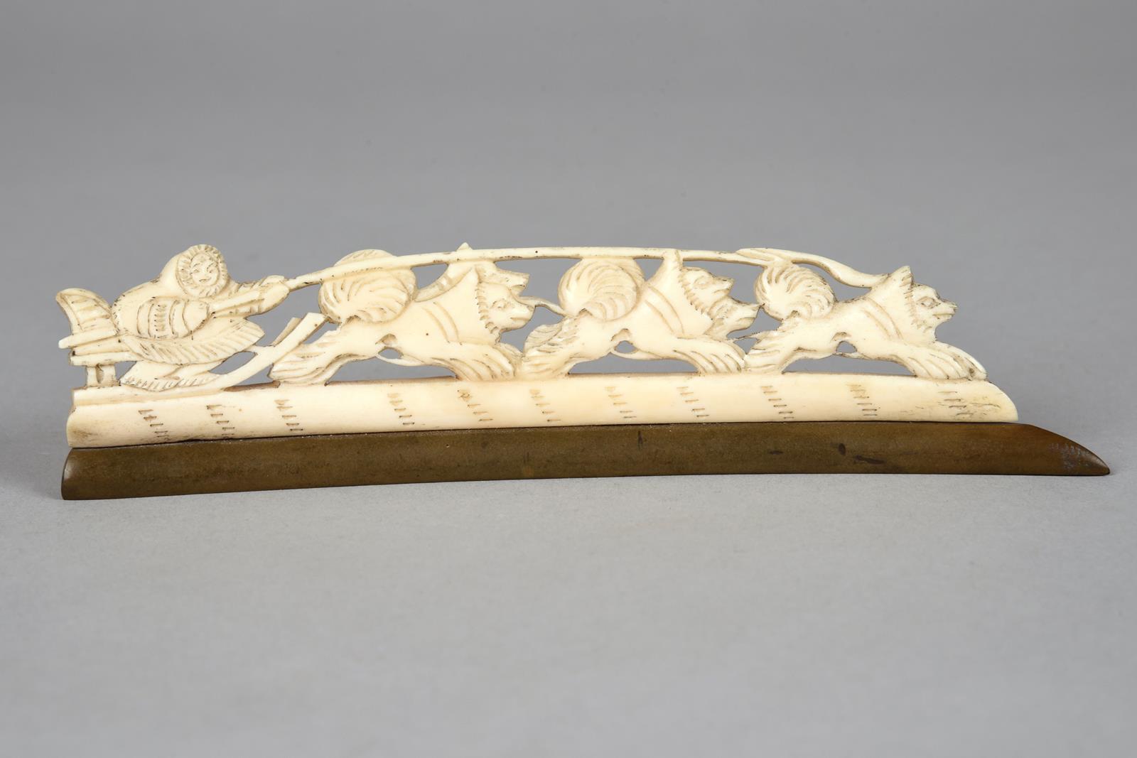λAn Inuit carved sleigh group walrus ivory, with a figure and five dogs, on a patinated baleen, 16.