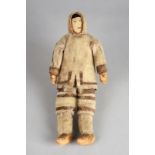 An Inuit doll Arctic with a woven head and wearing a seal skin parka and trousers, mittens and