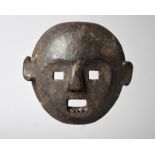 A Makonde mask Tanzania the mouth pierced for teeth, with a black encrusted patina, 15.5cm high.
