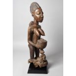 A Yoruba offering figure Nigeria with a standing female figure with remains of Reckitt's Blue to her