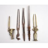 Five Indian hairpins brass and steel, all with two prongs, including a standing female figure, a