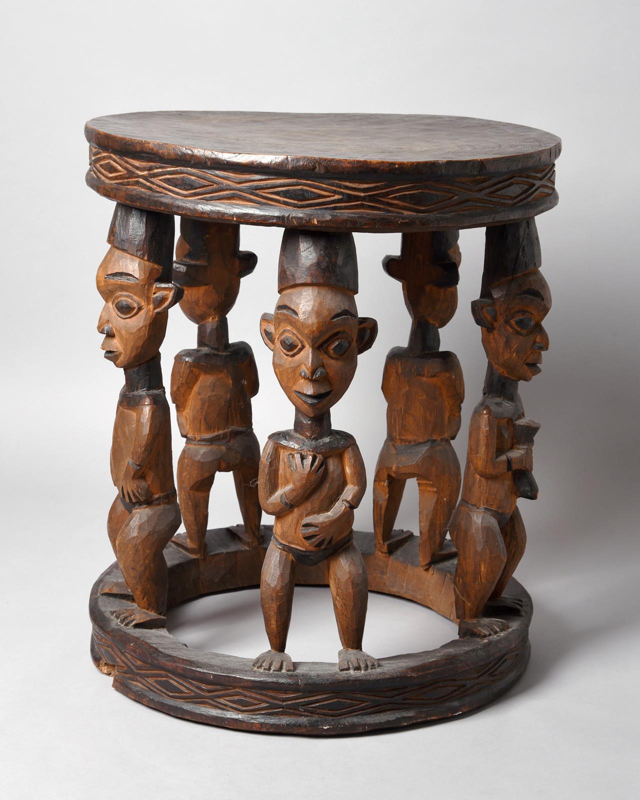 A Bamileke large stool Cameroon with five figural supports, two holding a horn, two with their hands