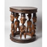 A Bamileke large stool Cameroon with five figural supports, two holding a horn, two with their hands