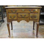 A Georgian mahogany lowboy enclosed by an arrangement of four drawers over a shaped apron and raised