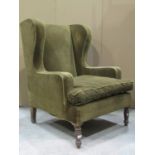 A vintage wing armchair upholstered in green dralon with later loose cover raised on turned forelegs