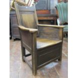 An 18th century oak enclosed chair with rectangular panelled back beneath shaped cresting rail, with