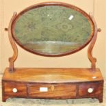 A Georgian mahogany toilet mirror of oval form raised on a bow fronted box base fitted with three