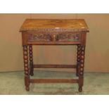 A 1920s oak side table fitted with a frieze drawer with carved green man mask cup handle and