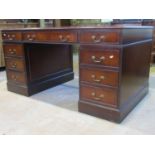 A reproduction Georgian style mahogany veneered kneehole twin pedestal desk with inset sage green