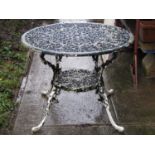 A painted and weathered cast aluminium garden terrace table of circular form with decorative pierced