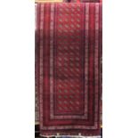 A Persian style wool runner with deep red field supporting multi octagonal lozenges, set within